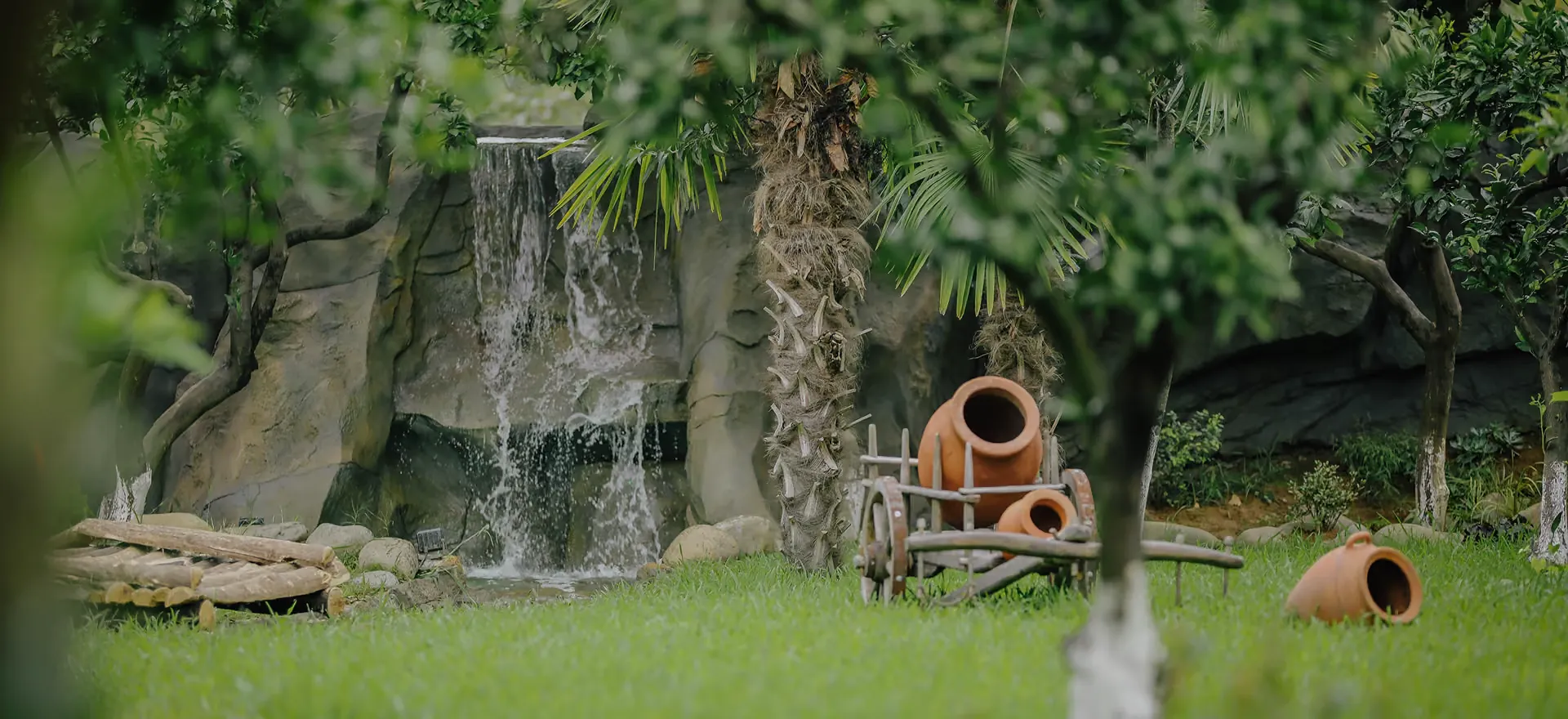 Clay qvevri resting on an old cart beside the waterfall in the estate garden