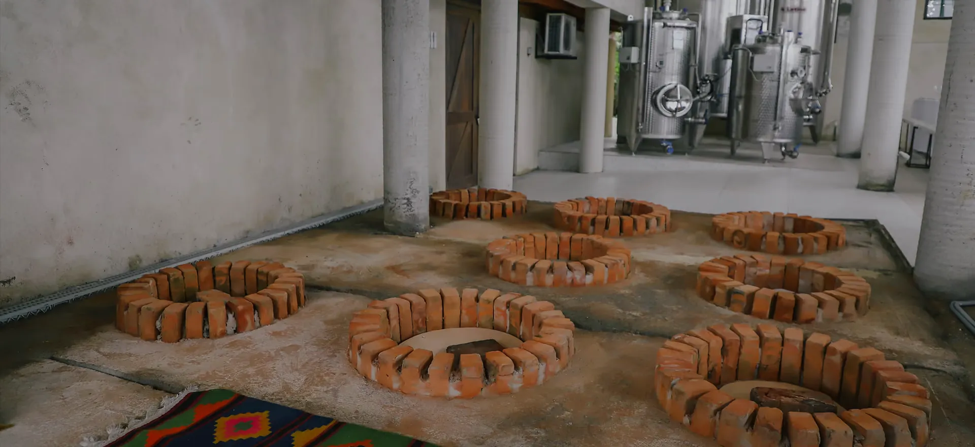 The cellar floor with qvevri set into the ground and steel tanks behind